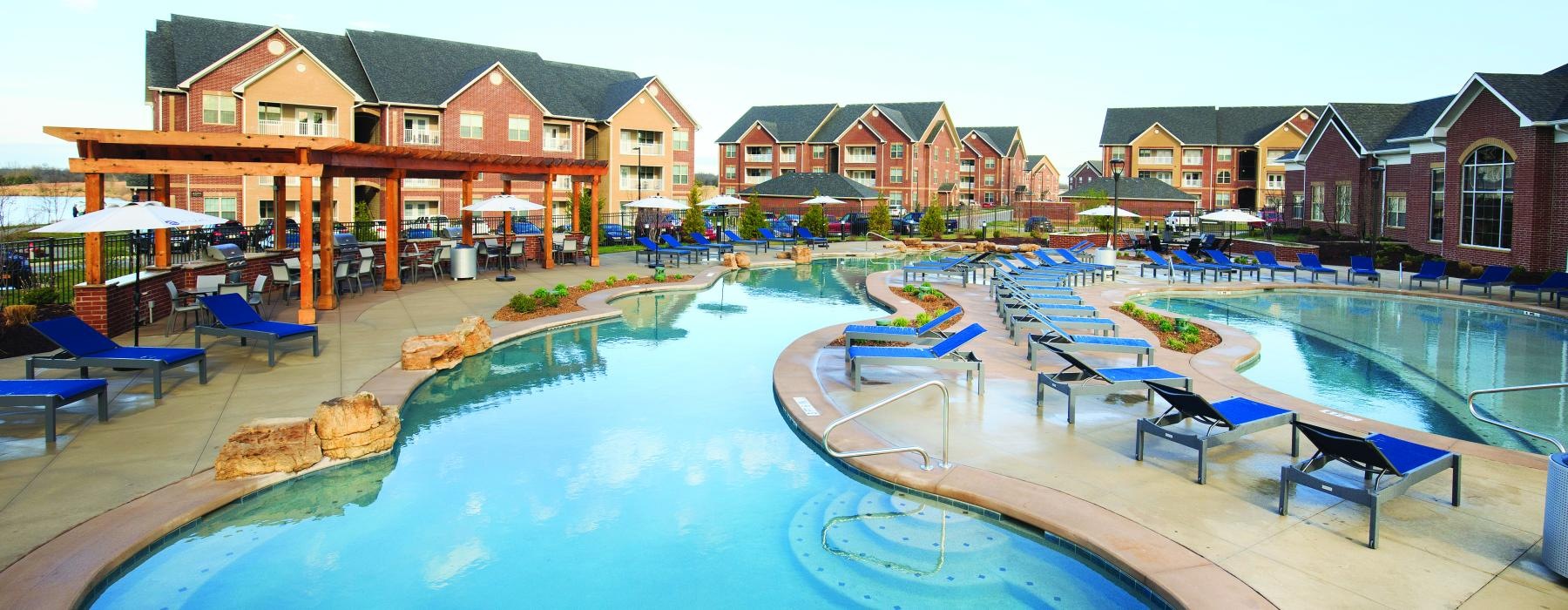 a swimming pool with a lounge chair and umbrellas by it