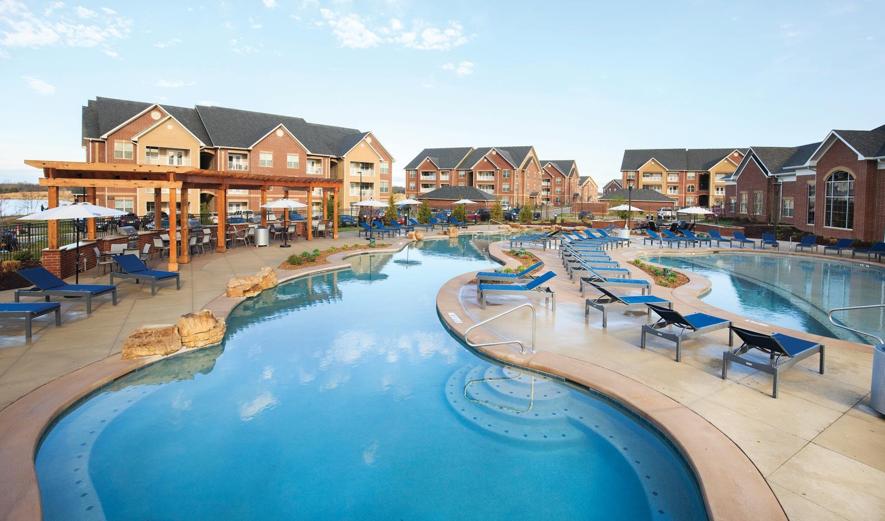 Relax and unwind poolside a pool with chairs around it