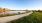 a river with grass and a building in the background